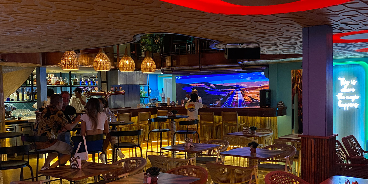 Street-floor bar at Paradise Soi 11 with a big screen and rattan lamps